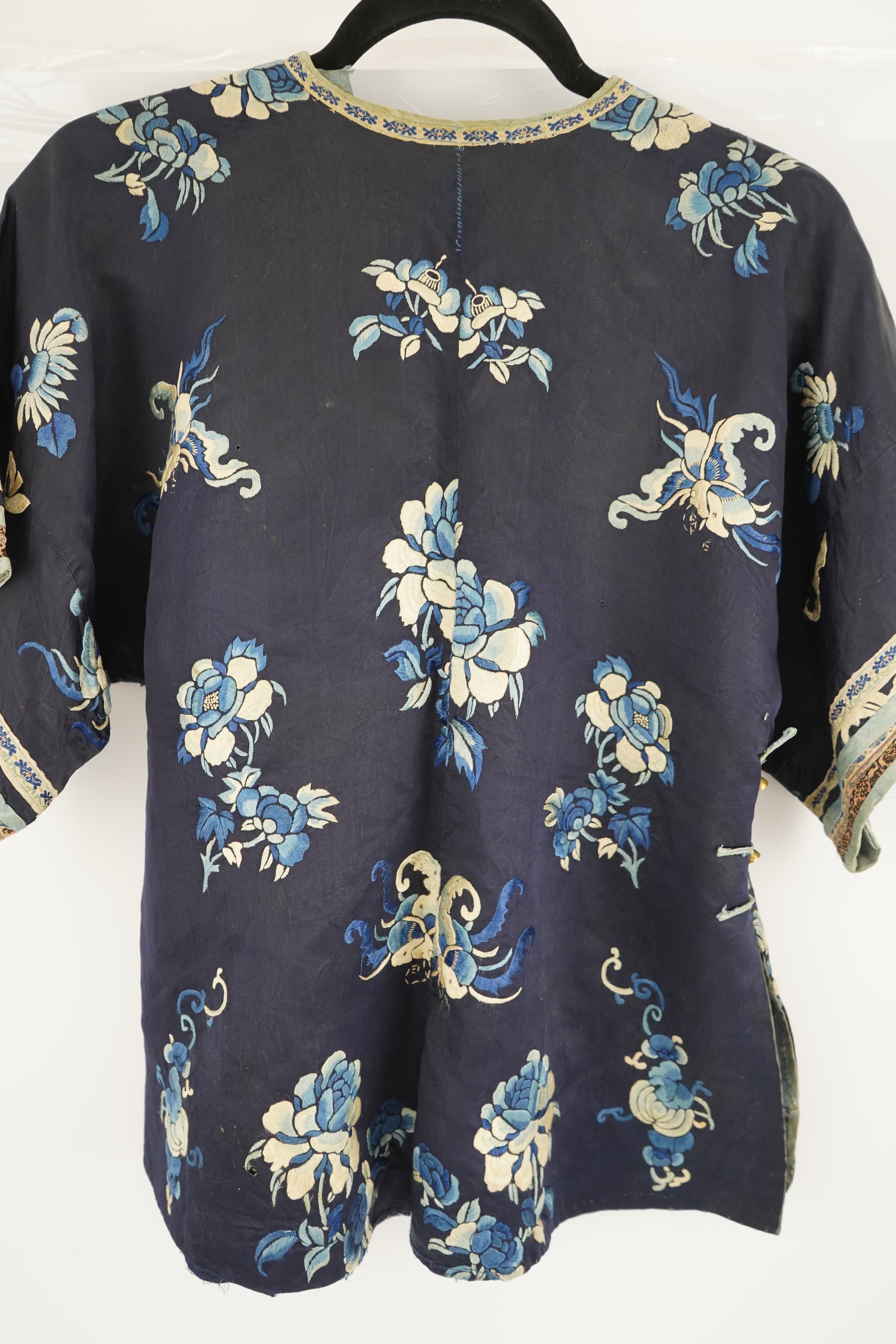 An early 20th century blue silk embroidered Chinese child’s robe, embroidered with bats and flower motifs, bordered with rows of silk braid. Condition - the original silk lining has been removed, it may benefit from bein